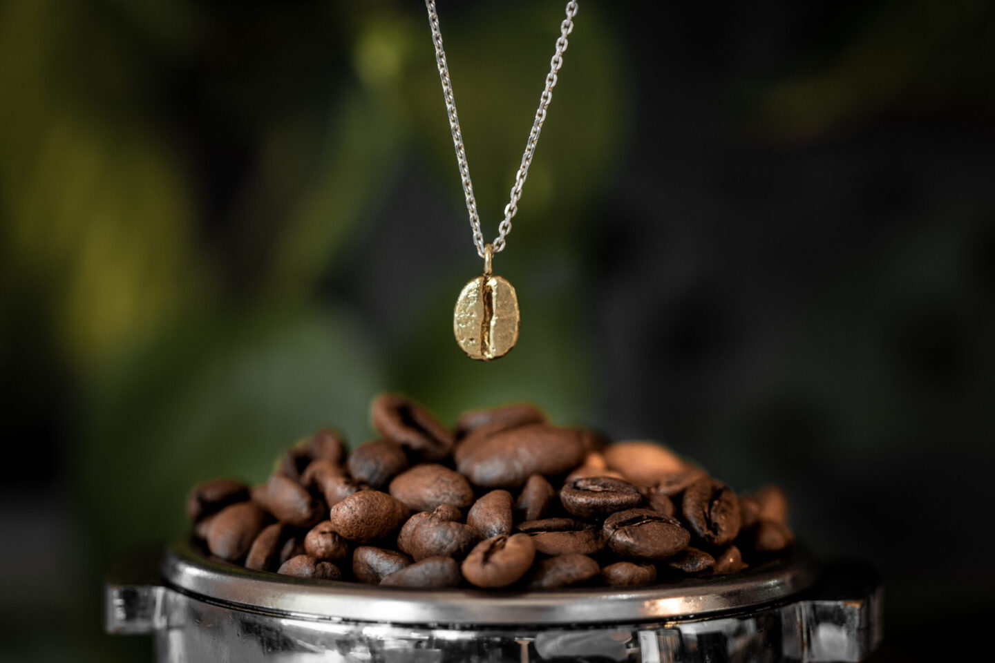 Řetízek s kávovým zrnem nad kupkou kávy